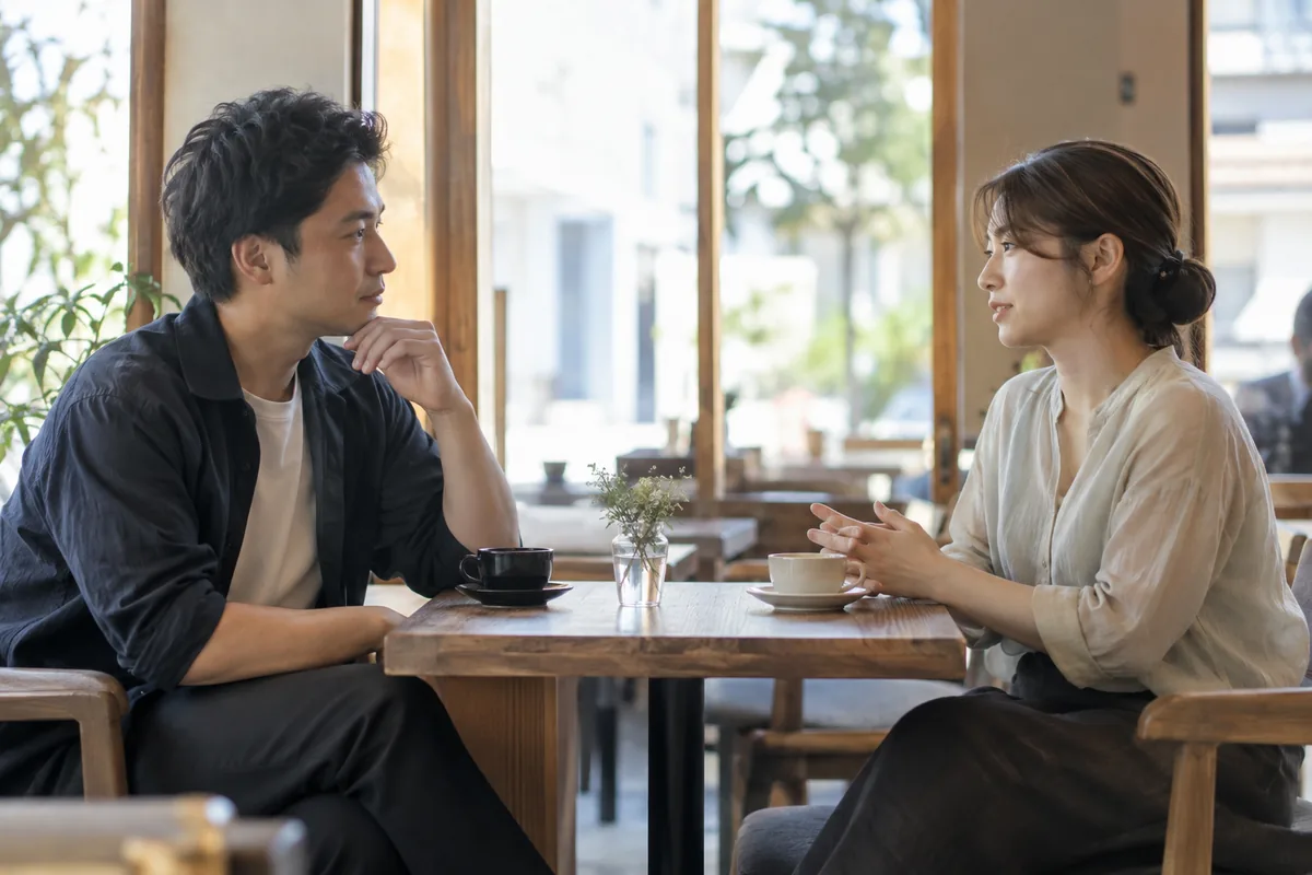 カフェで適度な距離を保ち付き合い方を話す成人の男女