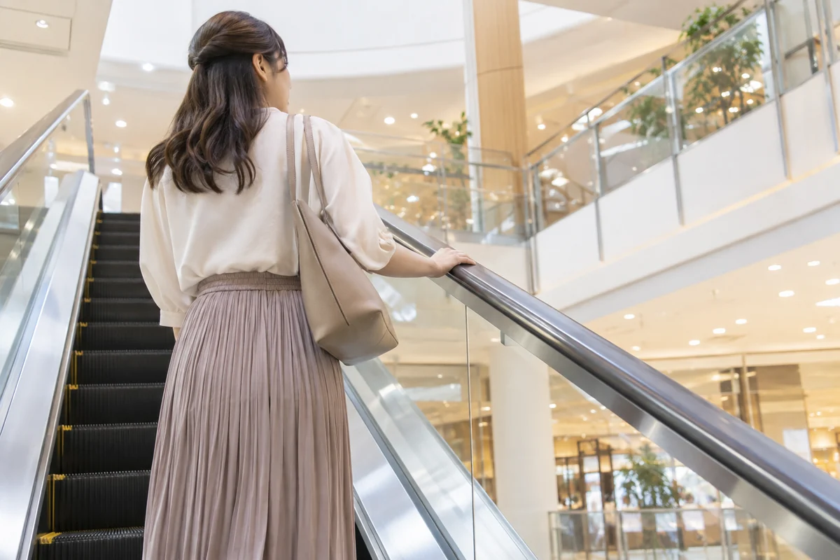商業施設のエスカレーターを利用する女性の写真調イメージ