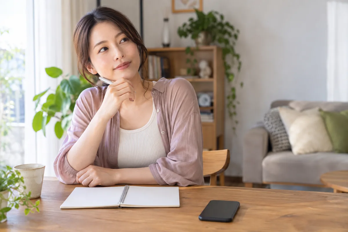 自宅の机で友達に伝えるタイミングを静かに考える女性