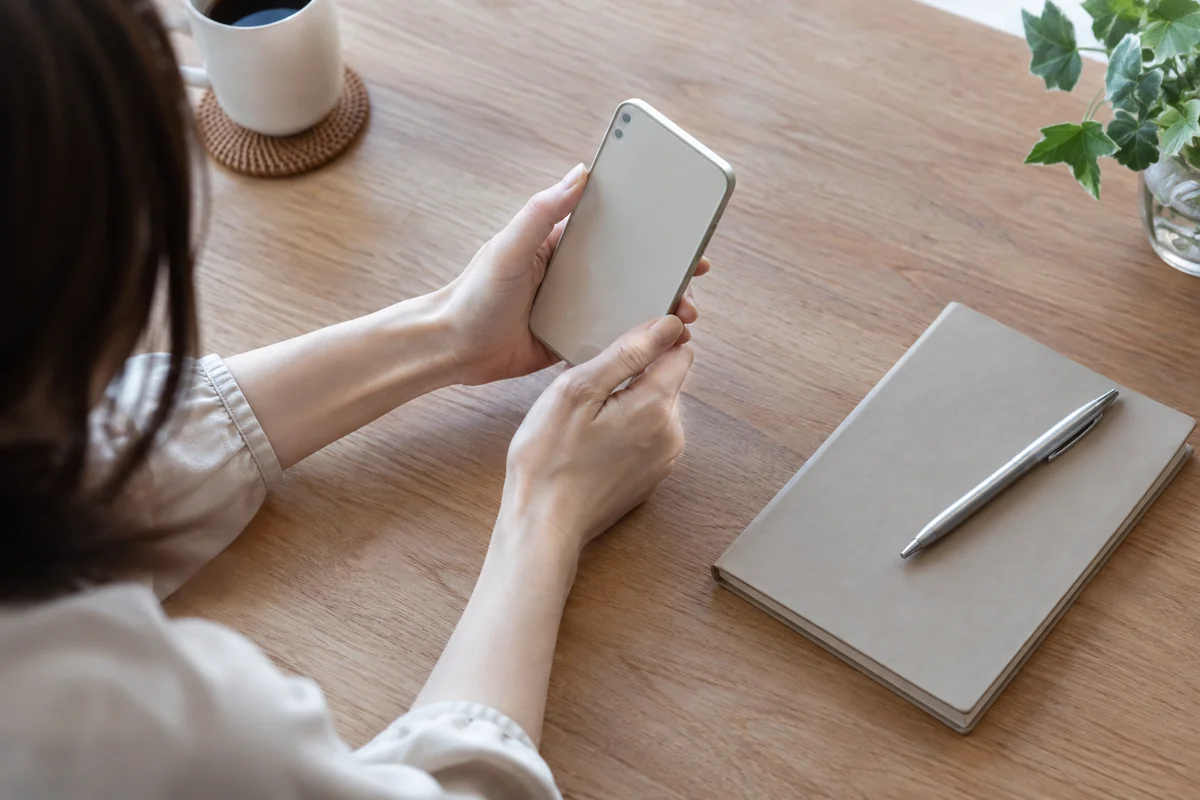 相談前にスマートフォンと手帳を確認する女性の手元のイメージ