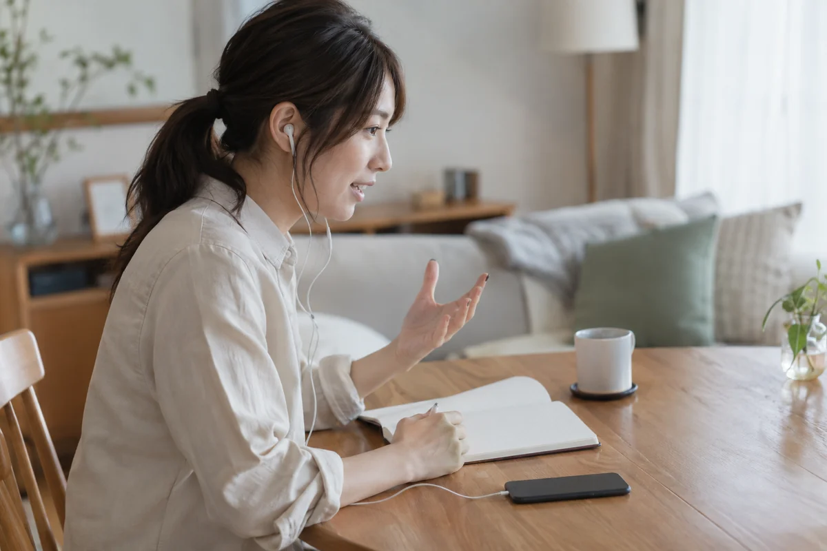 イヤホンで通話しながら相談内容を伝える女性のイメージ