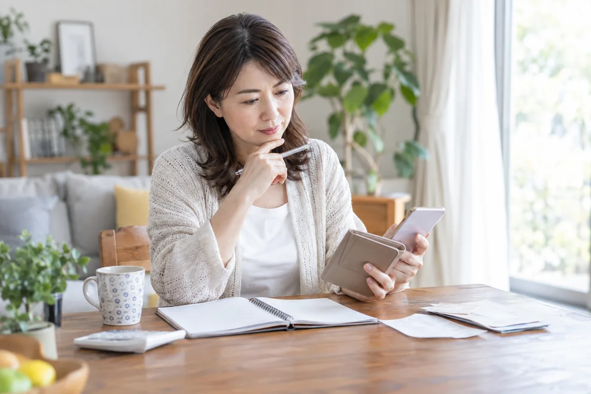 電話相談の支払方法と期限をノートで確認する女性