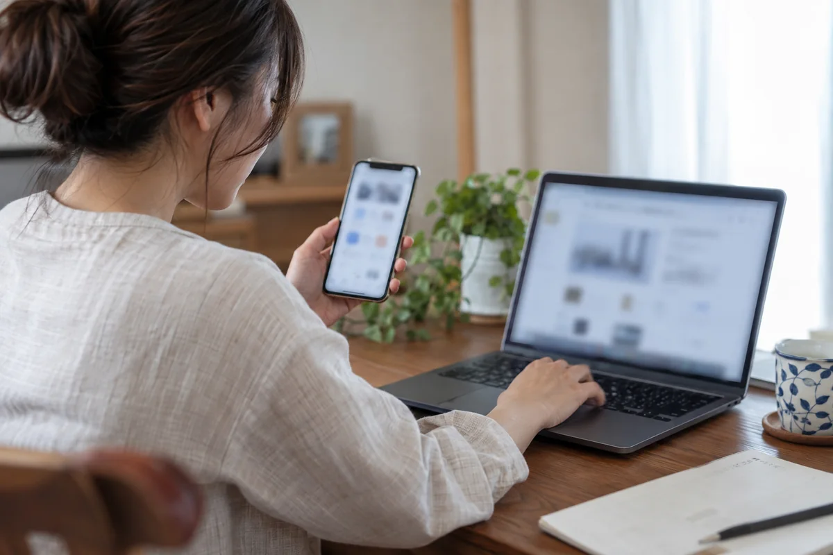 スマートフォンとパソコンの決済条件を確認する女性