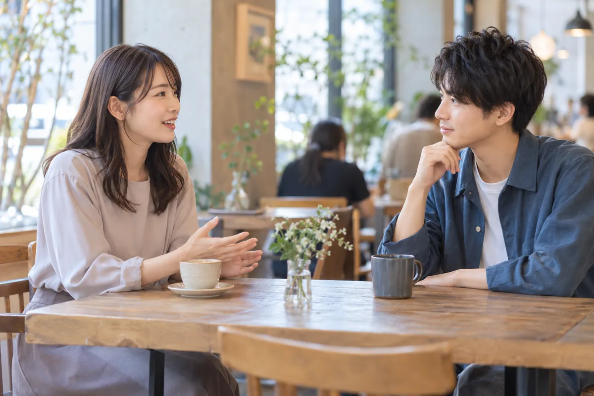 公共のカフェで適度な距離を保って会話する男女