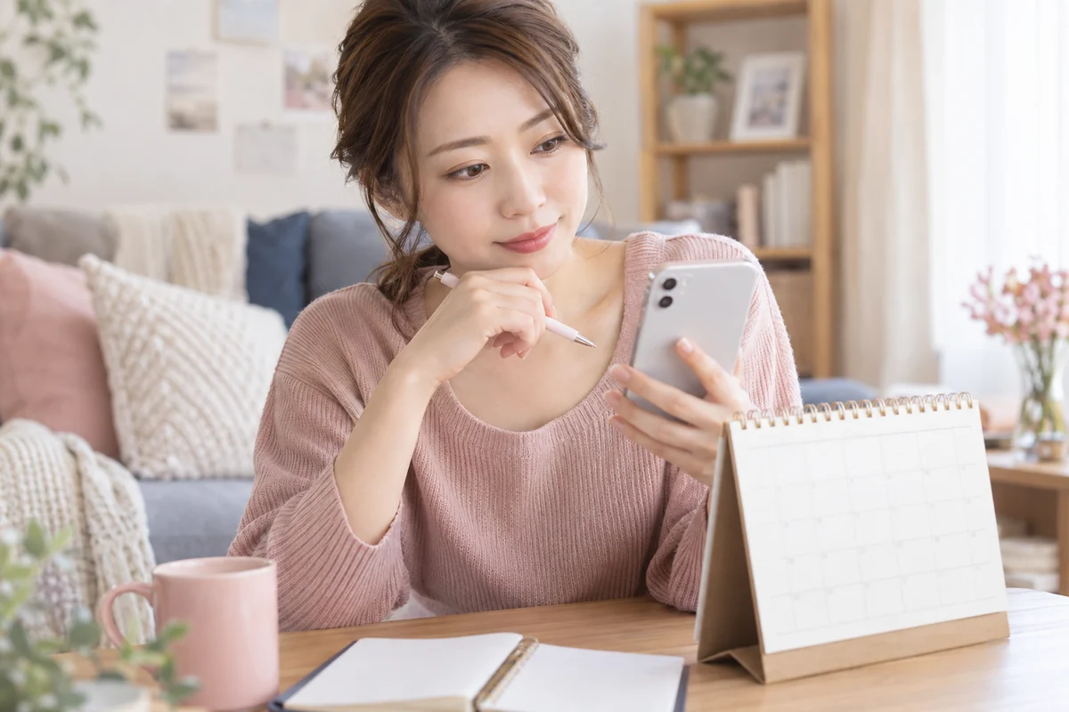 スマートフォンを見ながら相手の一貫した態度を振り返る女性