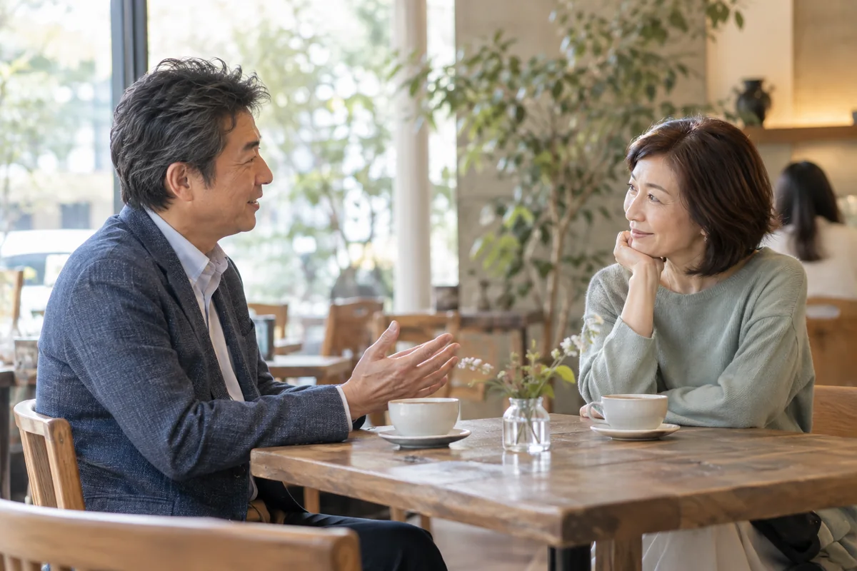 昼間のカフェで相手の話を丁寧に聞く50代の男女