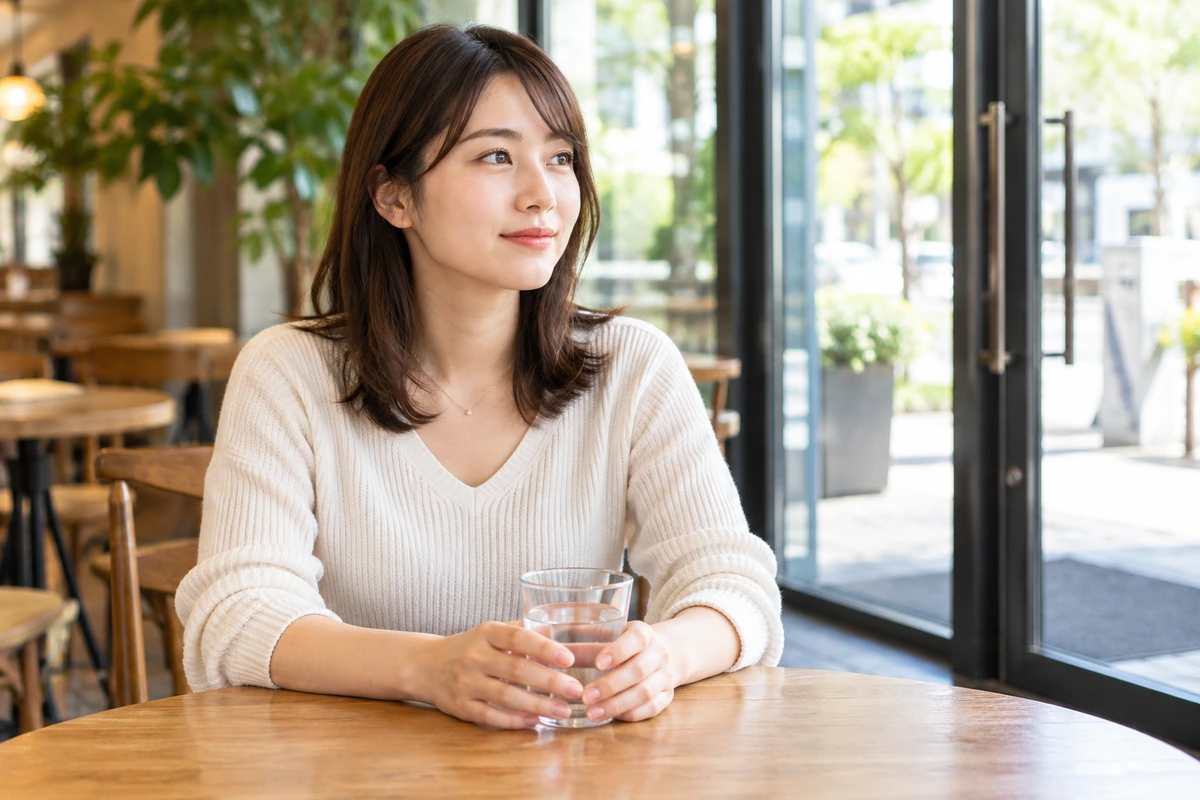 出入口に近い明るい店で落ち着いて待つ女性