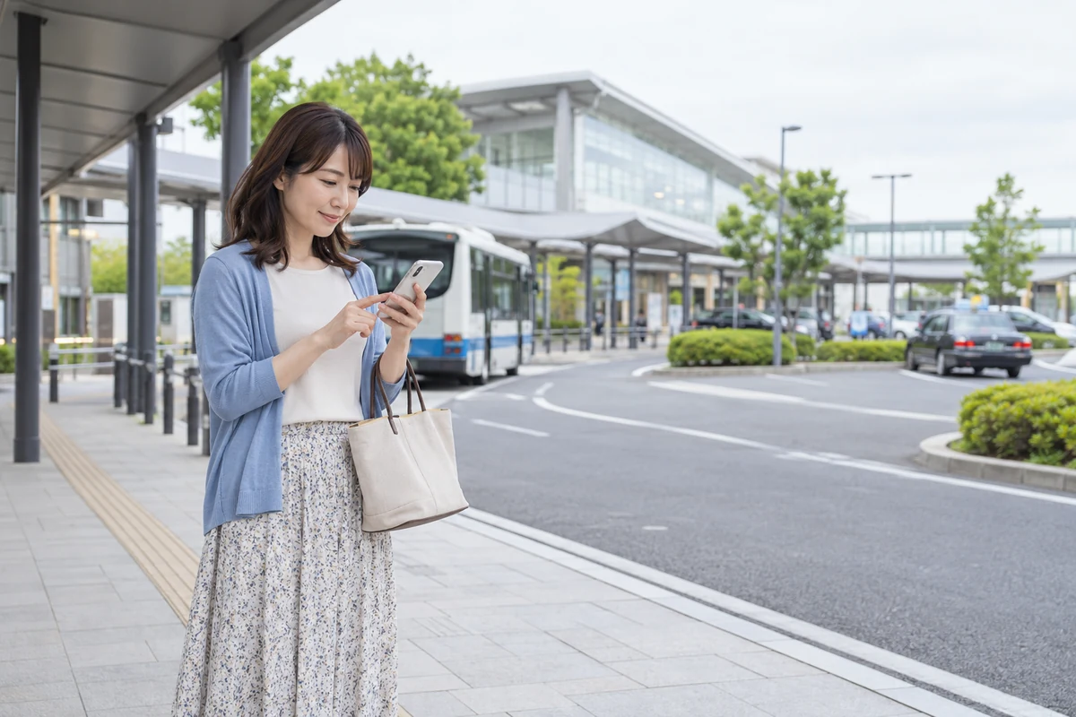 茨城の駅前でスマートフォンの経路を確認する女性
