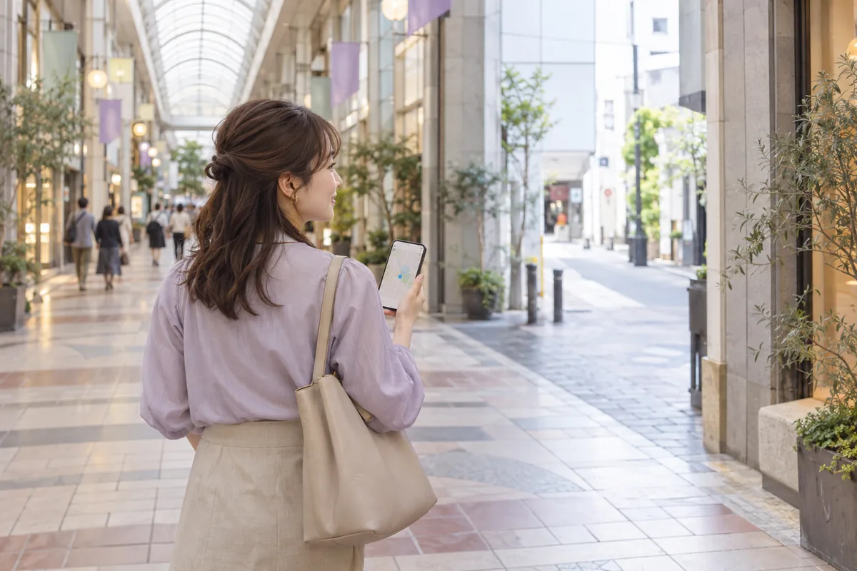 高松の商店街でスマートフォンの地図を確認する女性