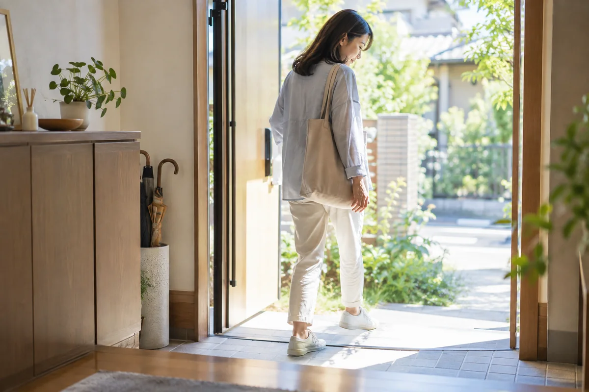 朝の玄関から外へ一歩踏み出す女性