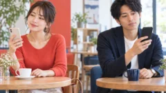 カフェでスマートフォンを見ながらTinderの口コミを検討する男女